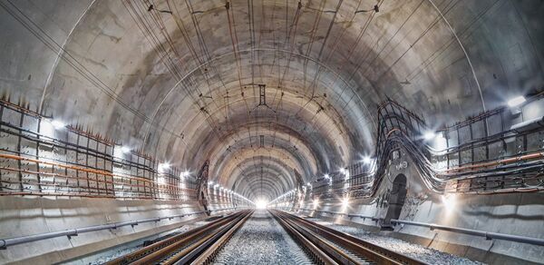 Binnenkant van een betonnen spoortunnel met bovenleidingsmasten en spoorrails