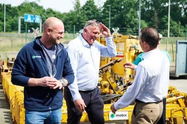 Drie Mobix collega's in gesprek op een zonnig moment op het Mobix terrein bij gele machines